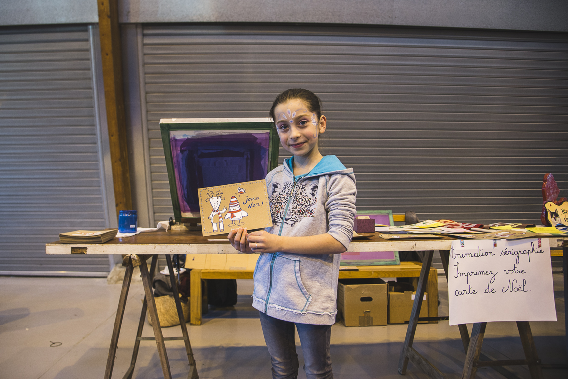 rozimages - photographie d'évènement - évènement communautaire - Marché de Noël 2015 - enfant montrant sa carte de voeux imprimée - Mondavezan, France