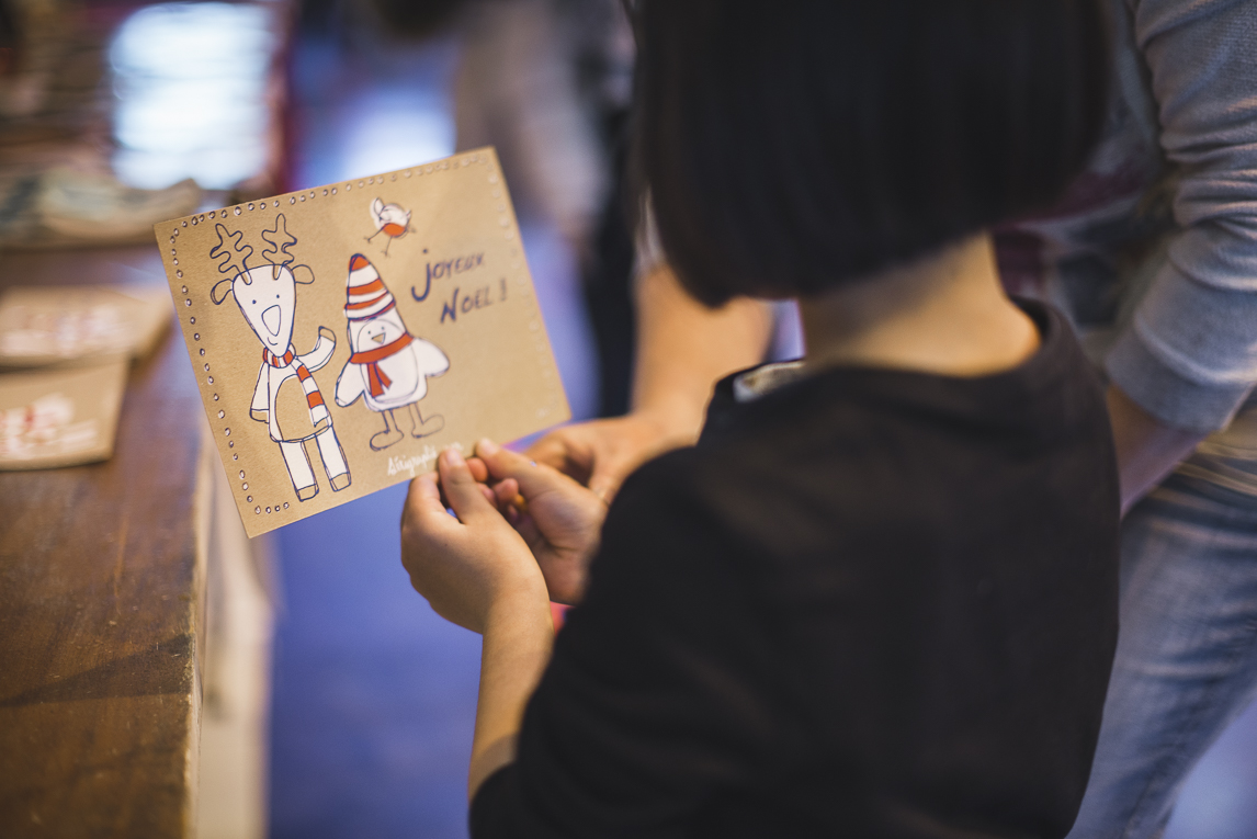 rozimages - photographie d'évènement - évènement communautaire - Marché de Noël 2015 - enfant regardant sa carte de voeux imprimée - Mondavezan, France