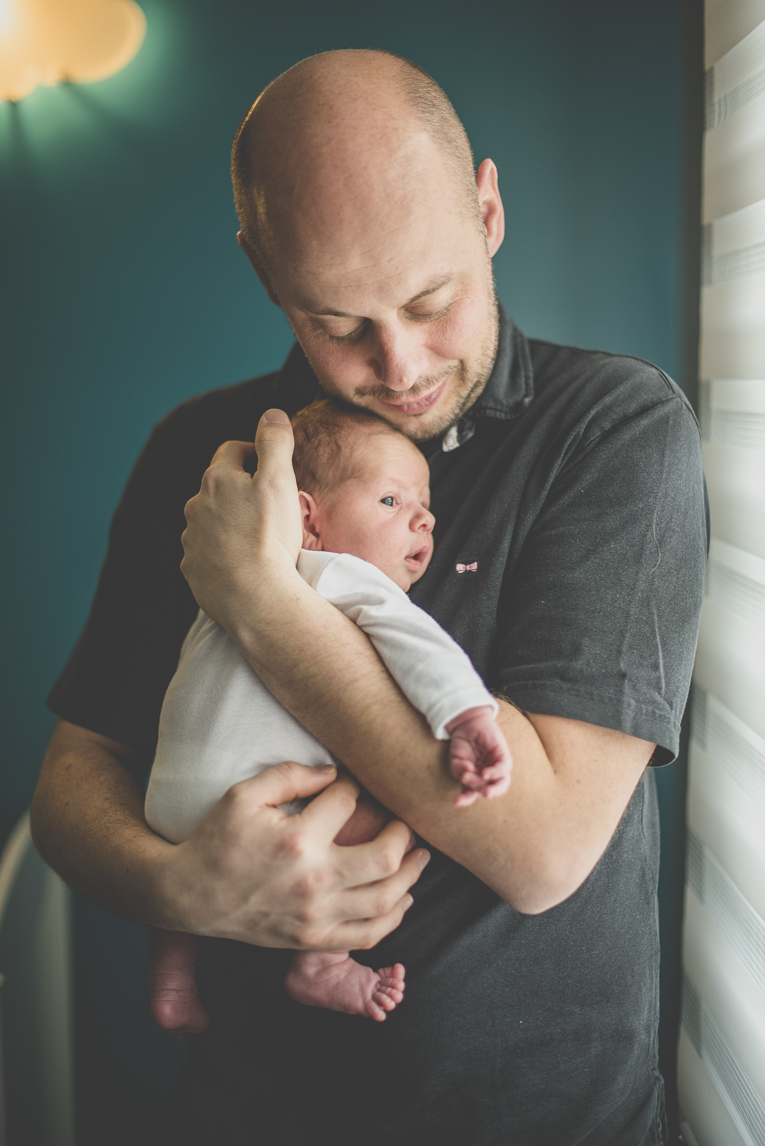 Séance photo nouveau-né Muret - papa tient bébé contre lui - Photographe naissance
