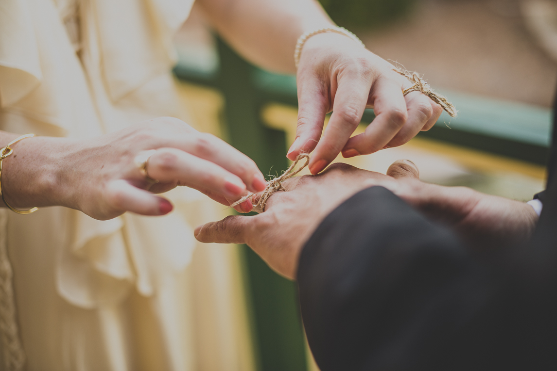 rozimages - photographie de mariage - gros plan sur les mains des mariés, la mariée fait un noeud avec un morceau de ficelle autour du doigt du marié - Broome, Australie