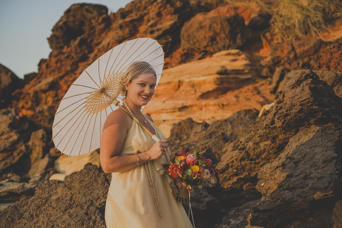 rozimages - wedding photography - bride smiling with umbrella, in front of rocks - Broome, Australia