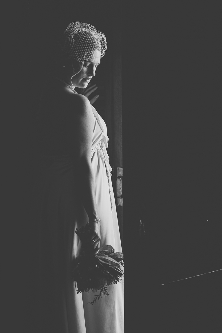 rozimages - wedding photography - bride standing in light in front of door, rest of picture is black - Broome, Australia