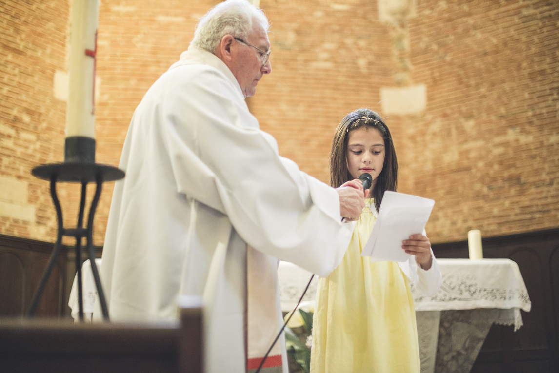 Baptême à Mondavezan - prêtre et fille parlant au micro - Photographe de famille