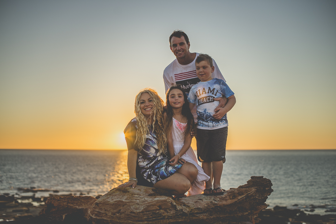 Family photo session - family posing on rocks in front of the sea - Family Photographer