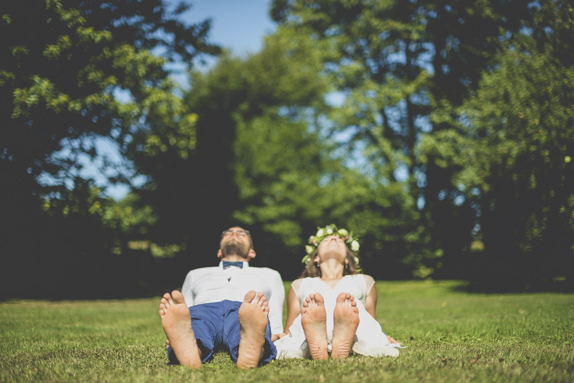 Reportage mariage Bretagne - Mariés allongés dans l'herbe - Photographe mariage