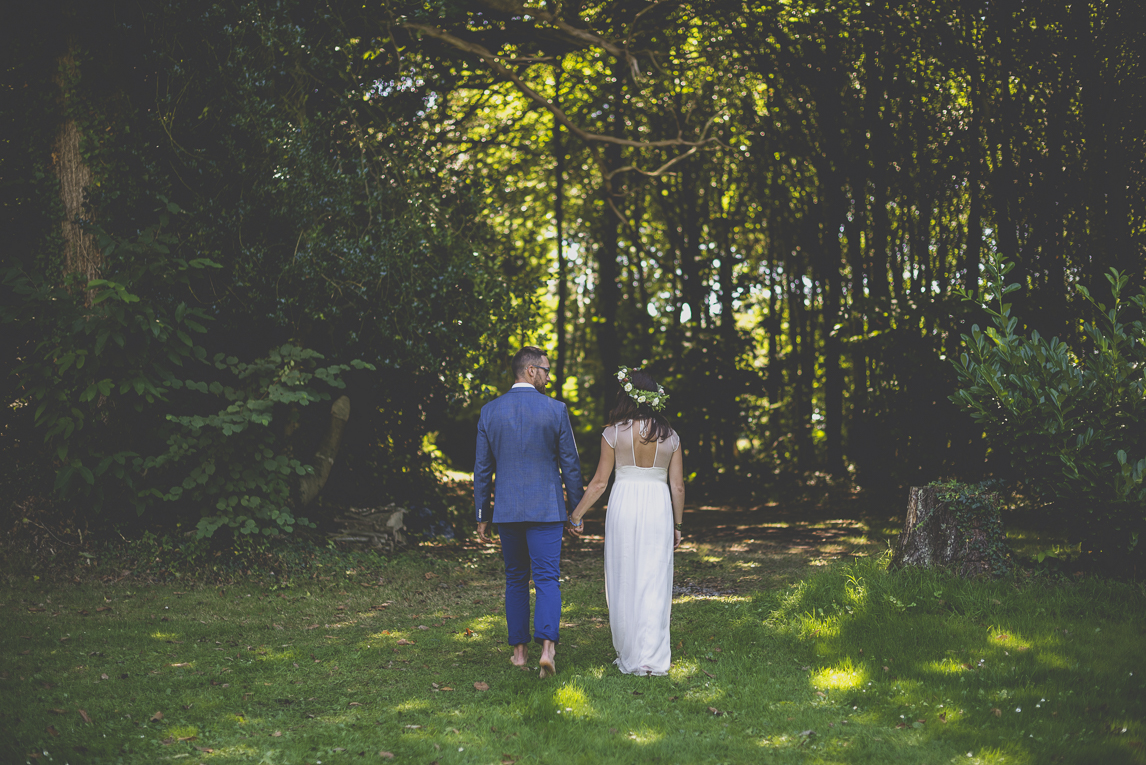 Reportage mariage Bretagne - mariés de dos marchant vers la forêt - Photographe mariage