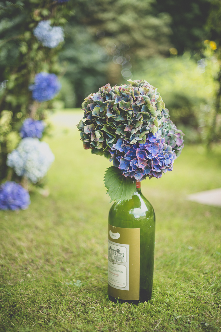 Reportage mariage Bretagne - bouquet d'hortensias dans une bouteille décorant la cérémonie - Photographe mariage