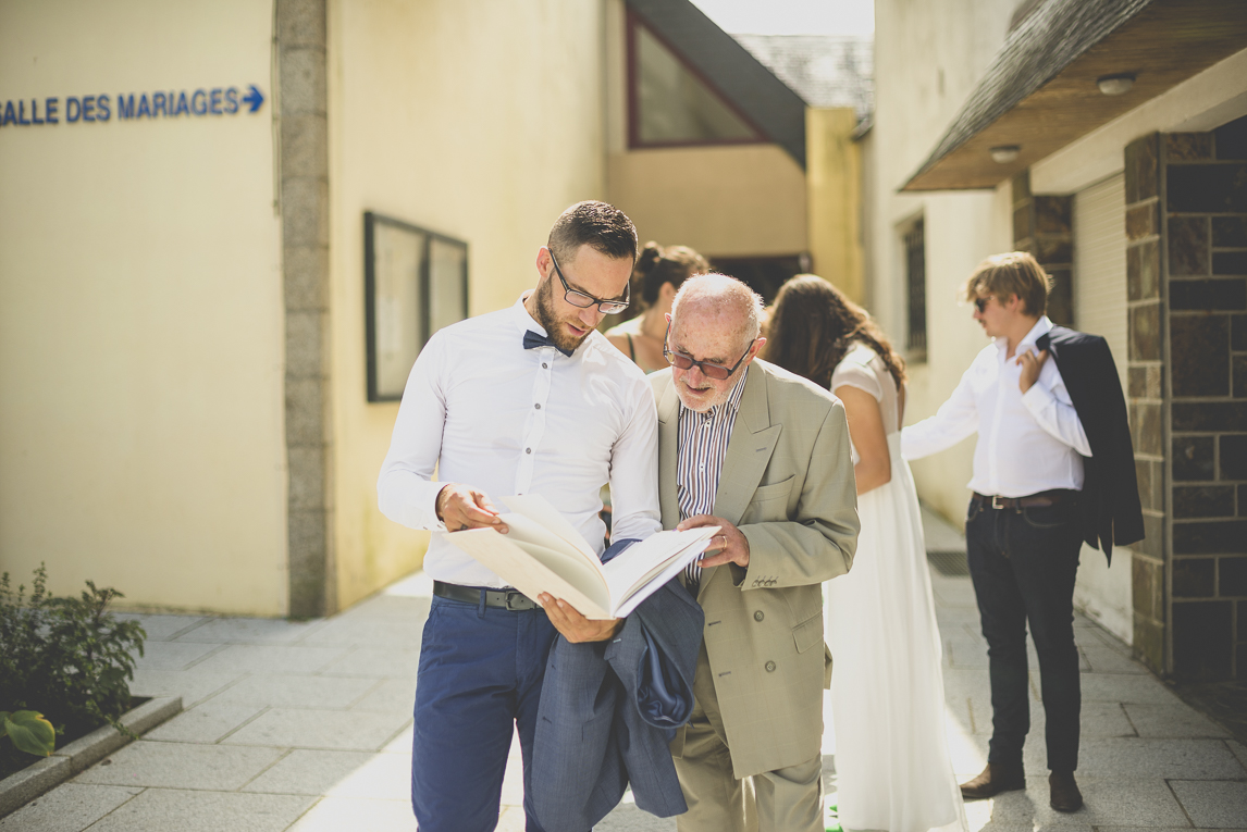 Reportage mariage Bretagne - marié et son grand-père regardant le livre de mariage - Photographe mariage