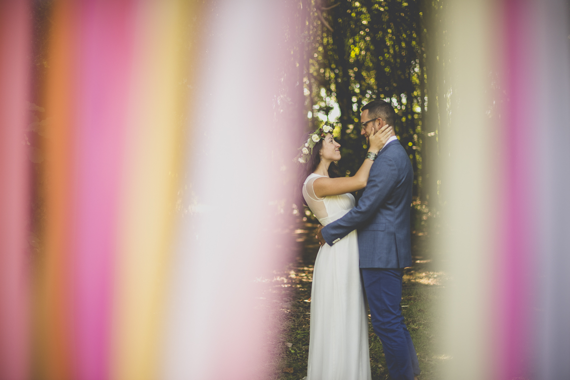 Reportage mariage Bretagne - Mariés se font un calin derrière des rubans - Photographe mariage