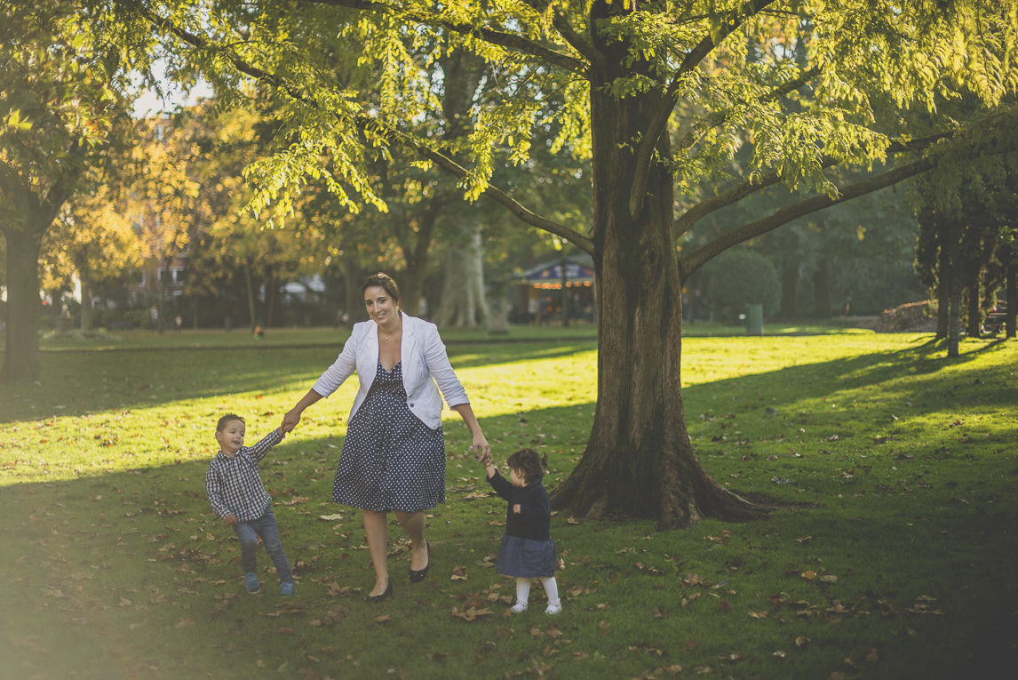 Séance photo famille - mère et ses deux enfants marchent en se donnant la main dans un parc - Photographe famille