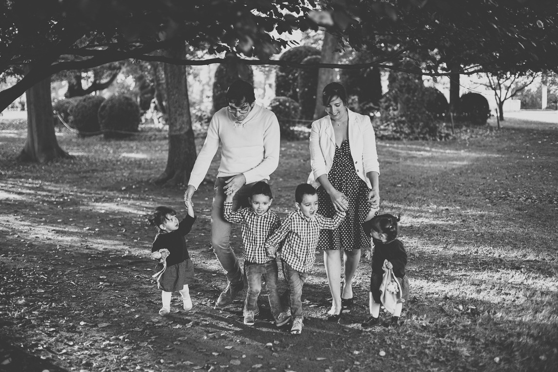 Family photo session - family with four children walk in a park hands in hands - Family Photographer