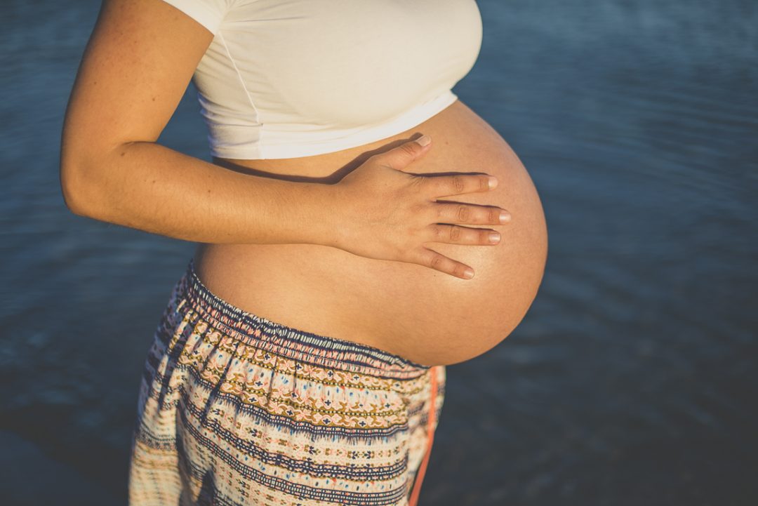 Séance photo grossesse à la plage - ventre rond d'une femme enceinte devant le bleu de la mer - Photographe grossesse