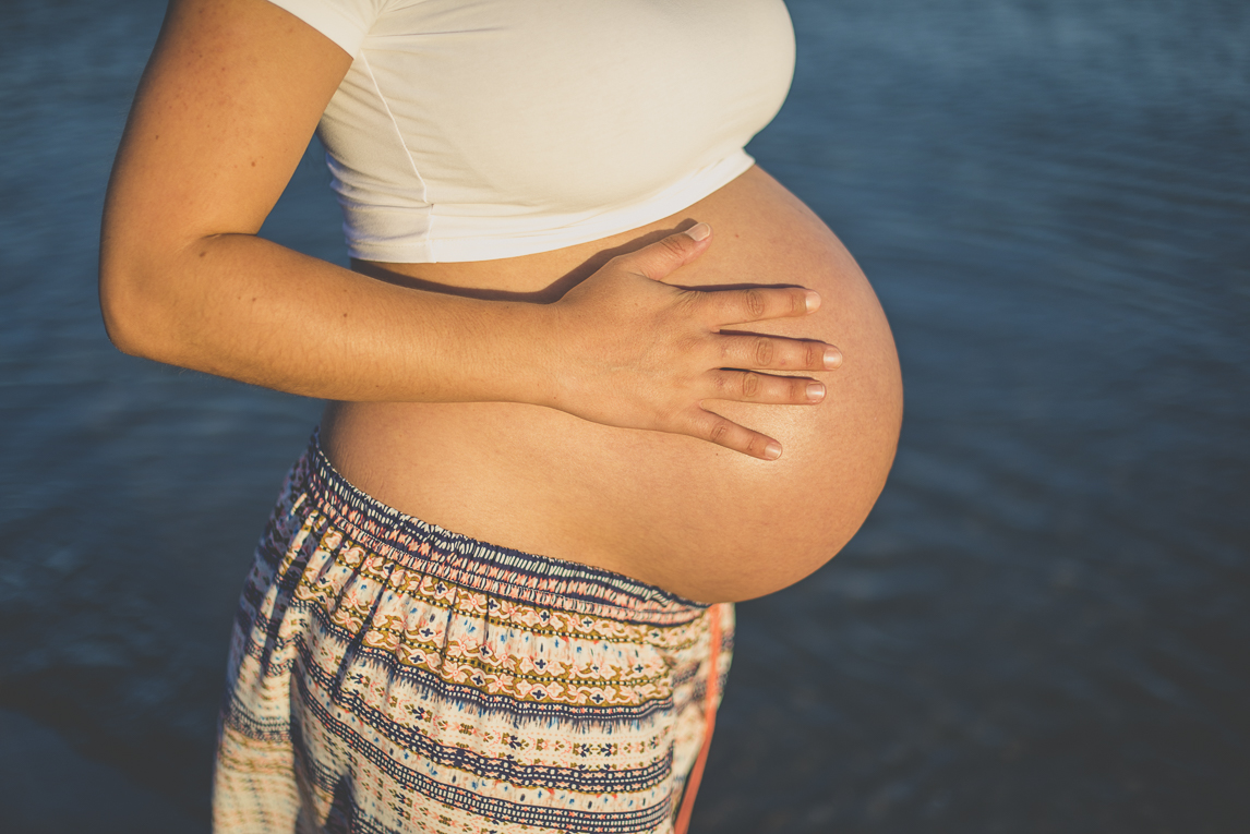 Séance photo grossesse à la plage - ventre rond d'une femme enceinte devant le bleu de la mer - Photographe grossesse