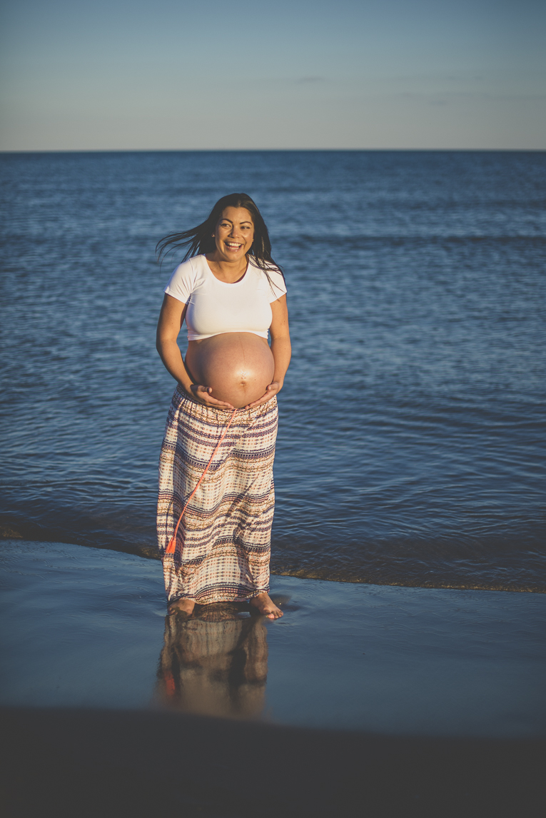 Séance photo grossesse à la plage - femme enceinte tient son ventre rond au bord de la mer - Photographe grossesse