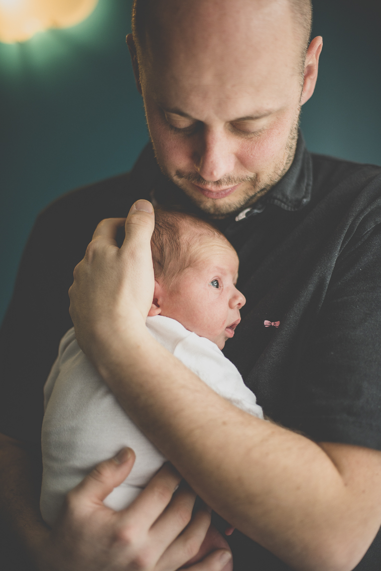 Séance photo nouveau-né Muret - papa tient bébé dans ses bras - Photographe naissance