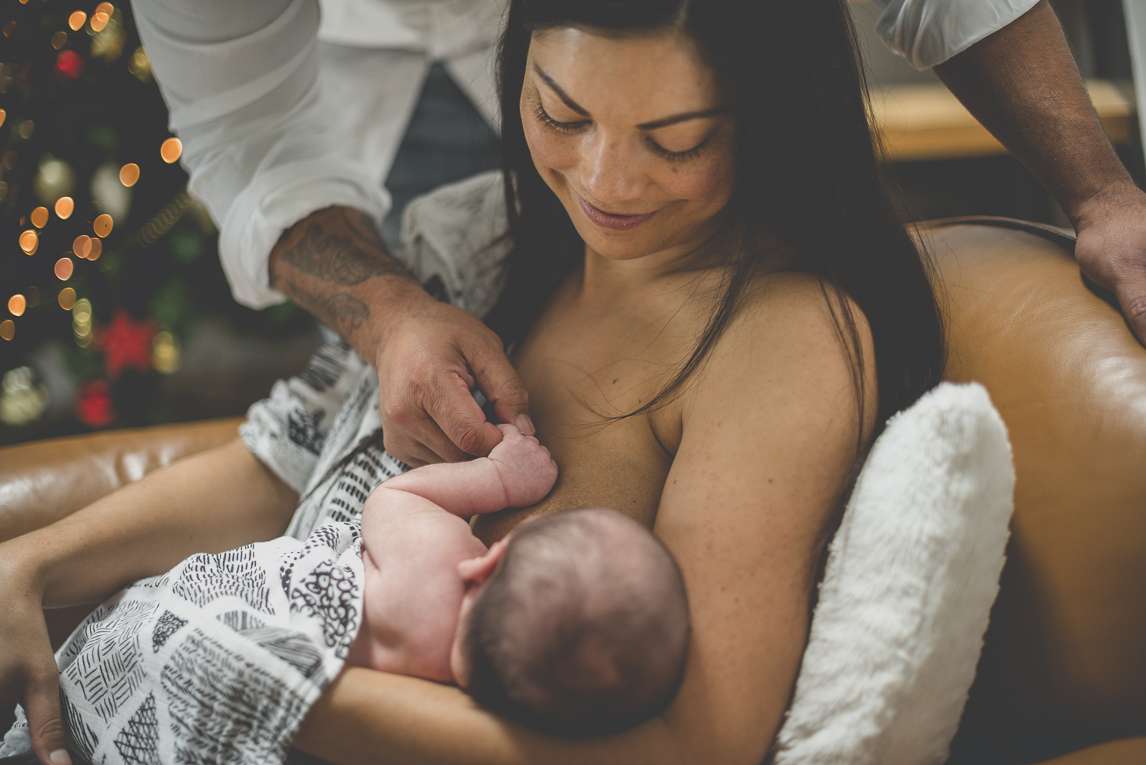 Séance photo naissance à domicile Occitanie - maman allaite nouveau-né et papa lui tient la main - Photographe naissance