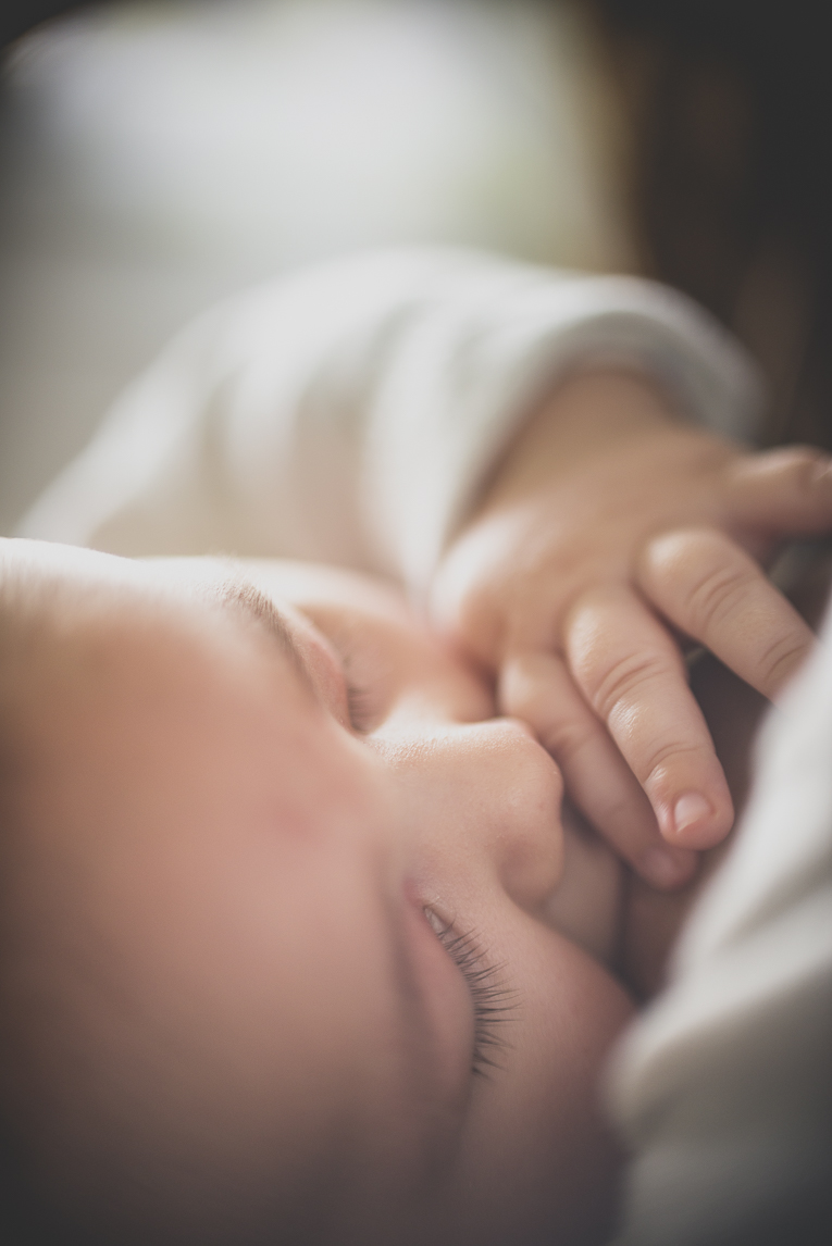 Séance bébé à domicile - gros plan visage bébé pendant l'allaitement - Photographe bébé