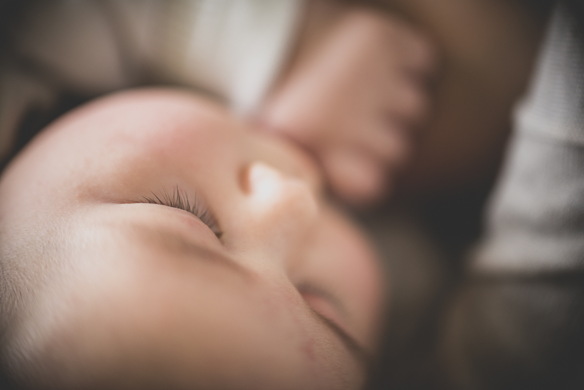 Séance bébé à domicile - gros plan visage bébé pendant allaitement - Photographe bébé