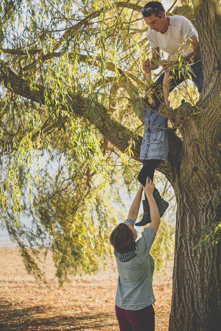 Séance photo en famille Ariège - parents aident petite fille à descendre d'un arbre - Photographe famille