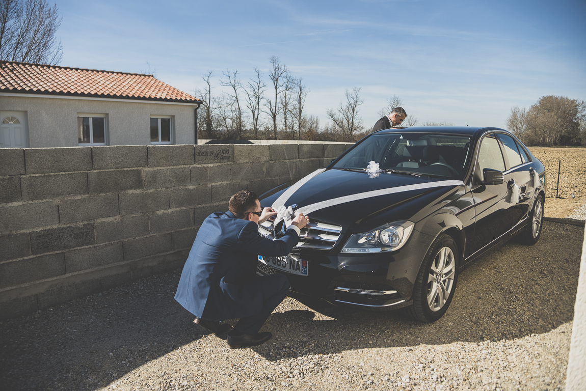 Reportage mariage hiver - le marié décore une voiture - Photographe mariage