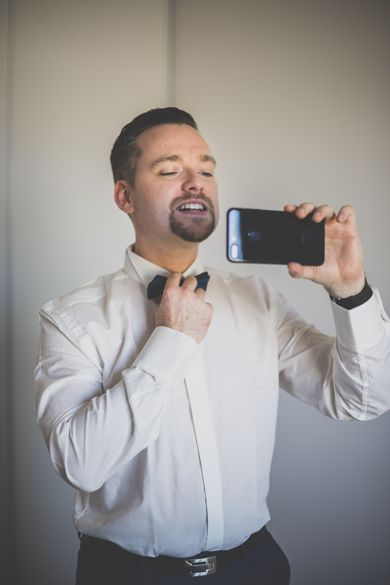 Winter Wedding Photography - groom looks at himself in the mirror of his phone - Wedding Photographer
