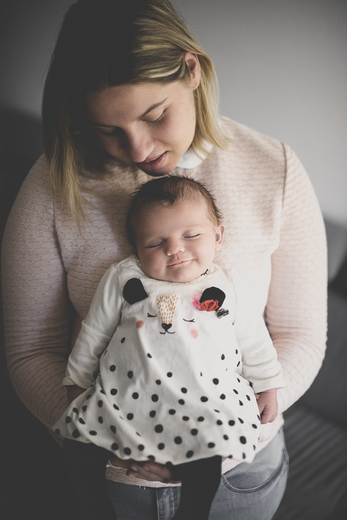 Séance nouveau-né à domicile Saint-Gaudens - bébé endormi et souriant dans bras de maman - Photographe nouveau-né