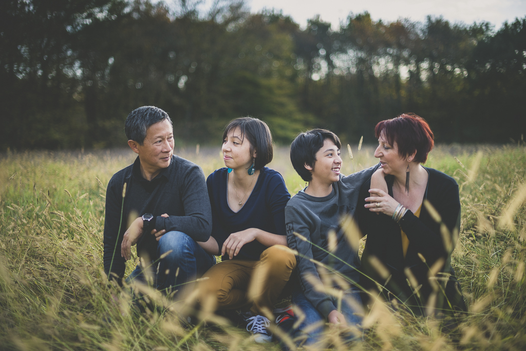 Séance famille en extérieur - famille assise dans les herbes hautes - Photographe famille