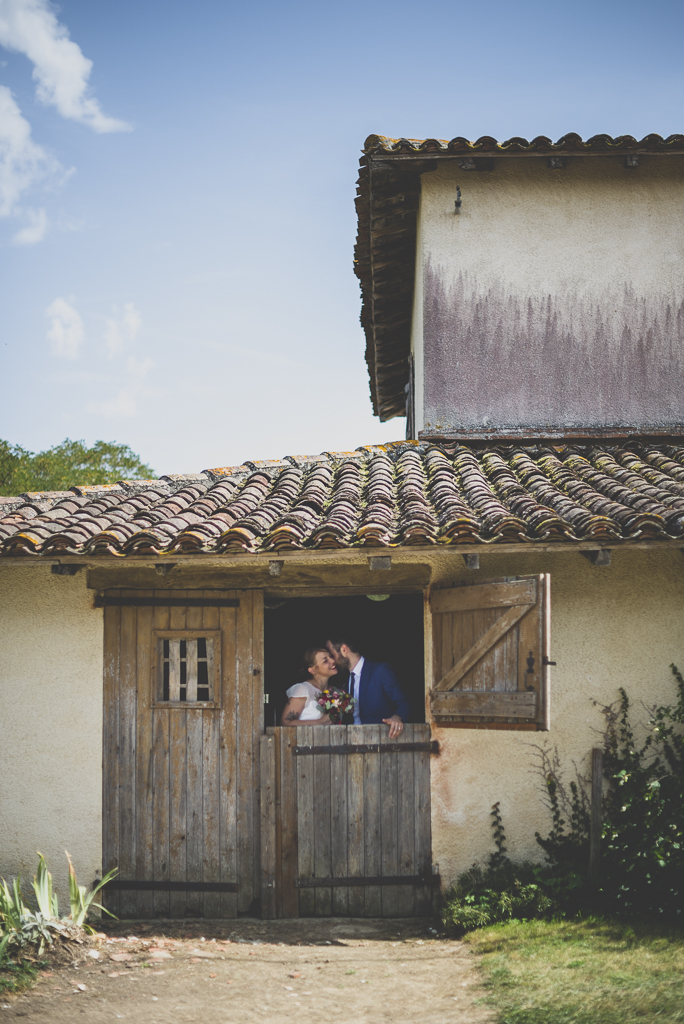 Reportage mariage Haute-Garonne - mariés derrière porte d'étable - Photographe mariage