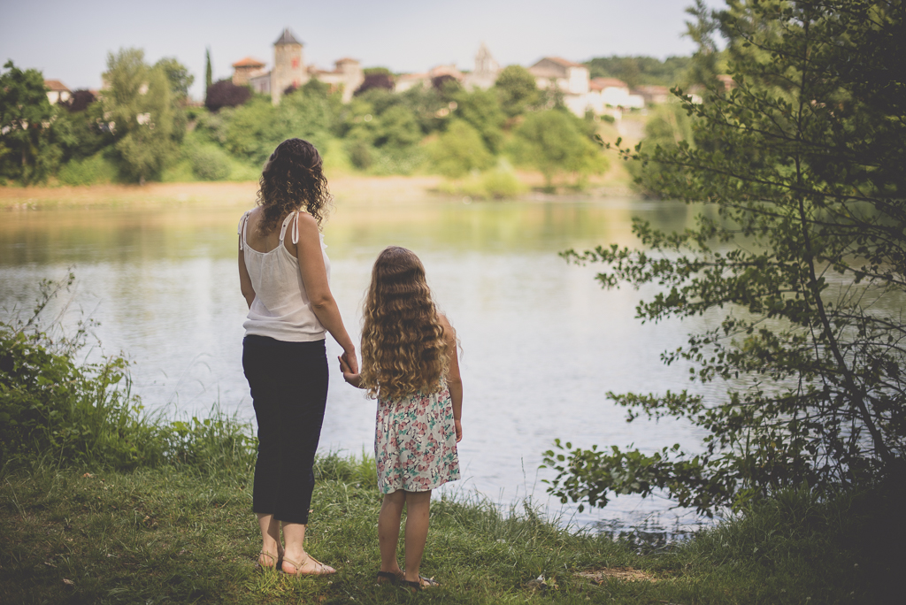 Séance famille Haute-Garonne - mère et fille se tiennent par la main et regardent la rivière - Photographe famille Toulouse