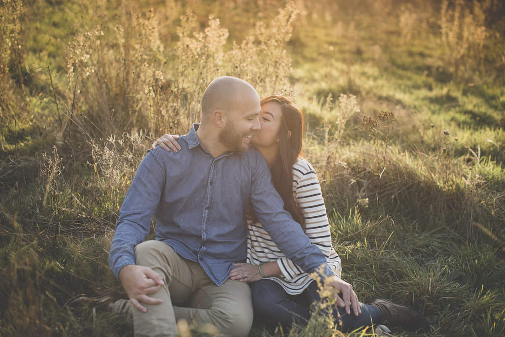 Couple photoshoot outdoors - couple assis dans plantes sauvages s'embrasse - Couple Photographer Toulouse