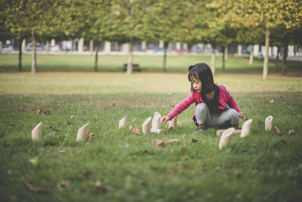 Reportage famille automne - petit fille ajuste les quilles du molkky - Photographe famille Haute-Garonne