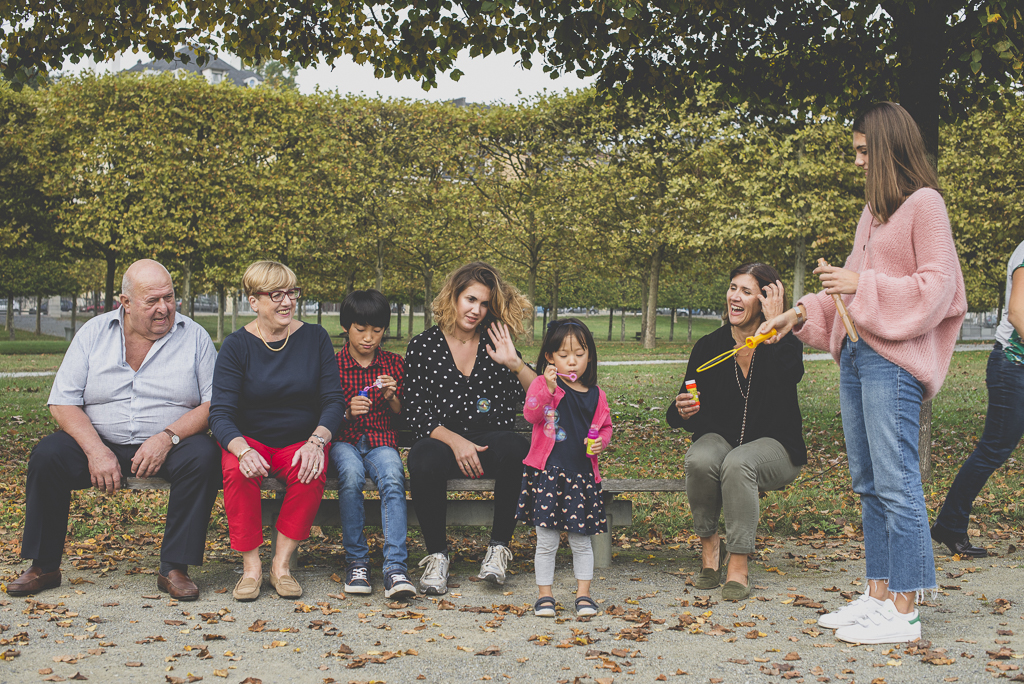 Reportage famille automne - famille assise sur banc fait des bulles de savon - Photographe famille Haute-Garonne