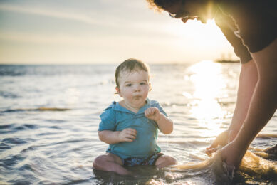 Séance photo famille à la plage - petit garçon assis dans l'eau - Photographe famille
