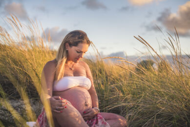Séance photo grossesse - femme enceinte assise parmis les herbes hautes - Photographe grossesse